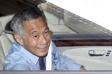 Singapore's Prime Minister Lee Hsien Loong winds down the window to wave to photographers as he arrives for a damages hearing against blogger Roy Ngerng at the Supreme Court in Singapore July 1, 2015. REUTERS/Edgar Su