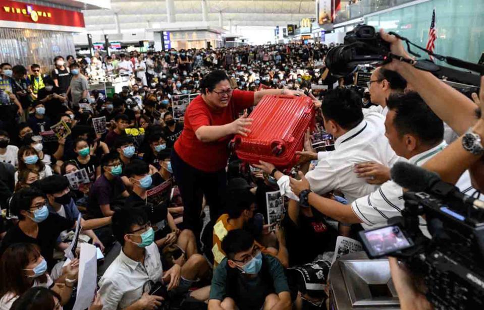 A Hong Kong tourist gives her luggage to security guards as she tries to enter the departures gate amid pro-democracy protests.