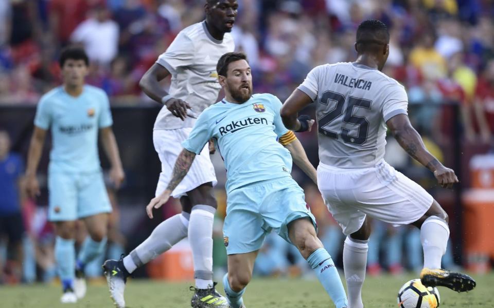 Lionel Messi (C) of Barcelona tries to get the ball from Antonio Valencia - Credit: AFP