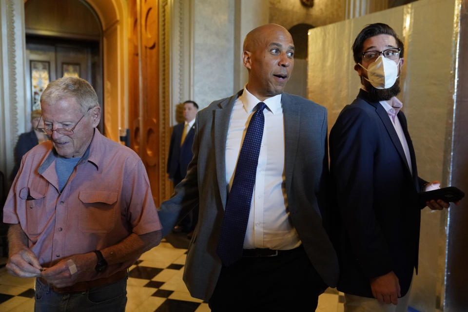 Sen. Cory Booker, D-N.J., center, and Sen. Jim Inhofe, R-Okla., left, step out of the Senate Chamber on Capitol Hill in Washington, Saturday, Aug. 6, 2022. (AP Photo/Patrick Semansky)