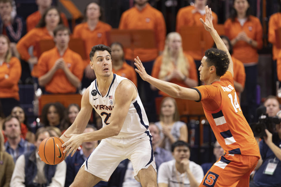 Virginia's Francisco Caffaro, left, defends the ball against Syracuse's Jesse Edwards (14) during the first half of an NCAA college basketball game in Charlottesville, Va., Saturday, Jan. 7, 2023. (AP Photo/Mike Kropf)