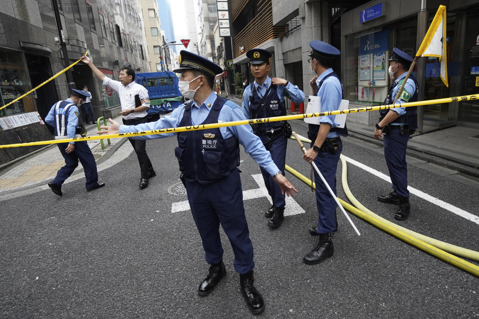 Police officers controls journalists near the scene of an explosion in a building Monday, July 3, 2023, in Tokyo. An explosion at a building in Tokyo’s commercial district of Shimbashi on Monday shattered windows and spewed smoke, according to media reports. (AP Photo/Eugene Hoshiko)