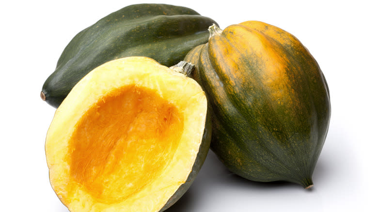 Halved seeded acorn squash with two whole acorn squash