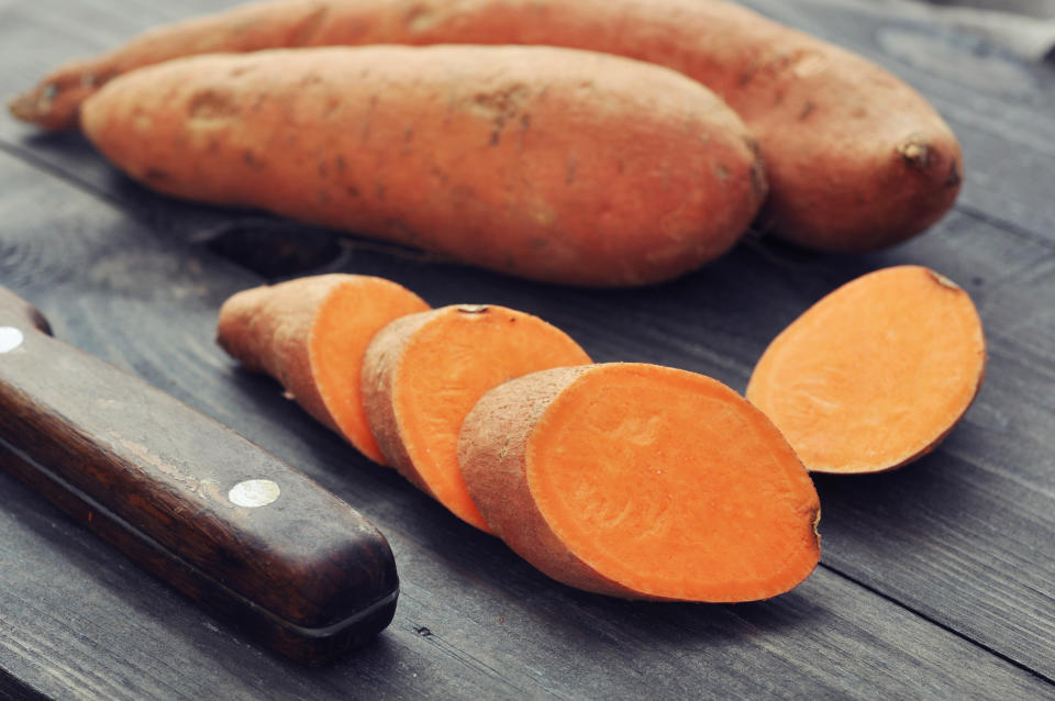 Raw sweet potatoes on wooden background closeup