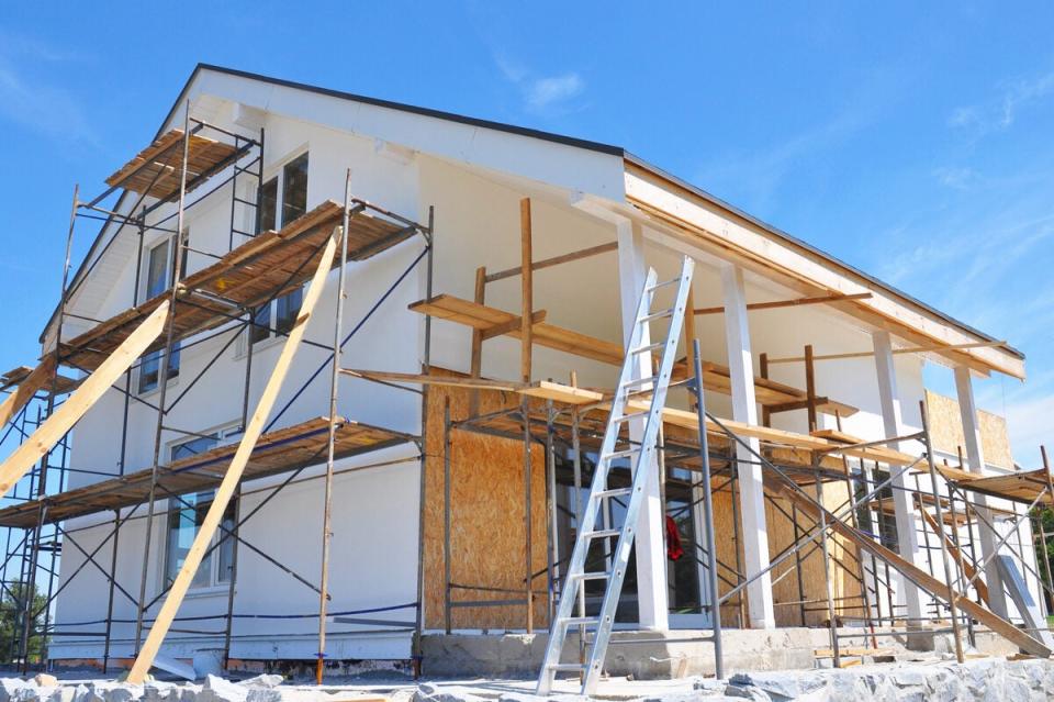 White home being remodeled with ladders and platforms.