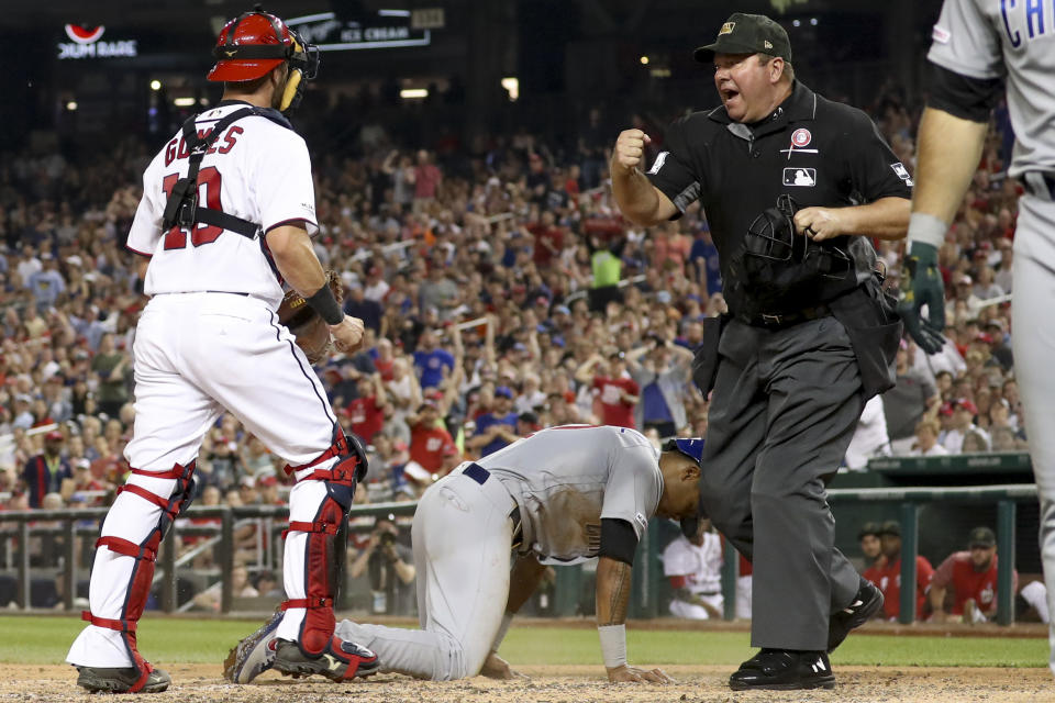 Umpire Sam Holbrook calls out Chicago Cubs' Addison Russell (27) after Washington Nationals catcher Yan Gomes (10) tagged him out after a passed ball to end the top of the fifth inning of a baseball game Saturday, May 18, 2019, in Washington. (AP Photo/Andrew Harnik)