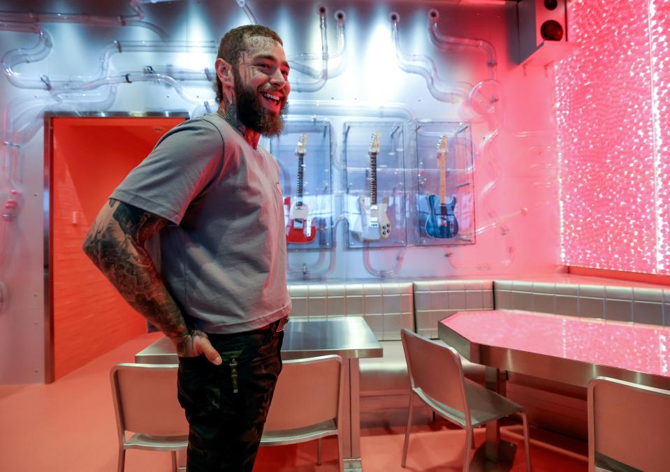 Post Malone shows media around a remodeled Raising Cane’s Restaurant, designed by the singer, in Midvale on Thursday, April 13, 2023. Some of his guitars hang on the wall behind him. | Kristin Murphy, Deseret News