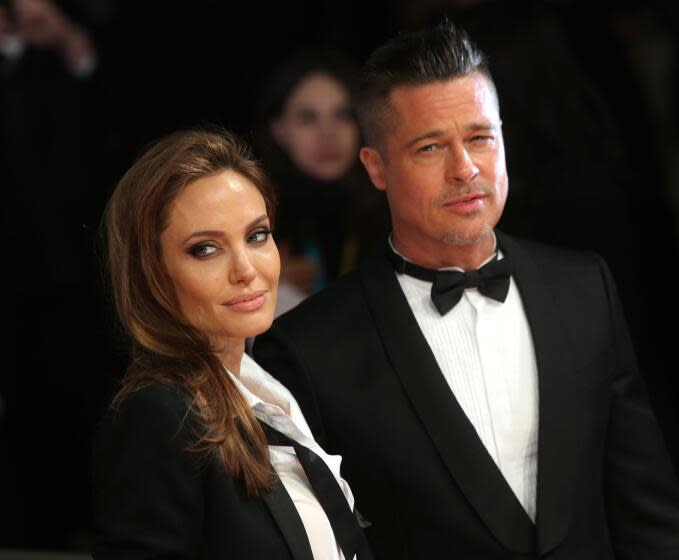 Actors Angelina Jolie and Brad Pitt pose for photographers in black tuxedos