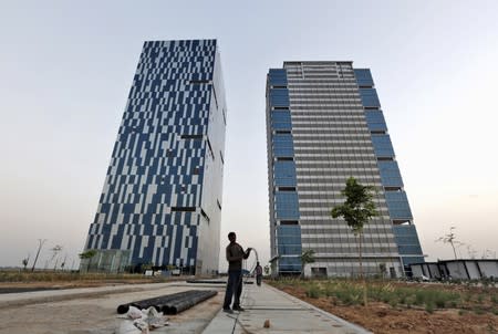 FILE PHOTO: A worker folds cable of welding machine in front of two office buildings at Gujarat International Finance Tec-City at Gandhinagar, in Gujarat