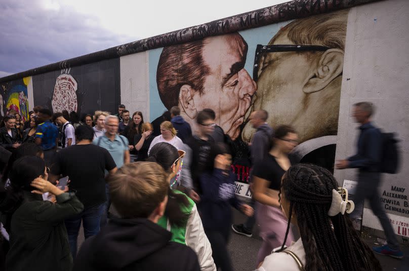 Tourists gather in front of the popular 'My God, Help Me to Survive This Deadly Love' mural at the East Side Gallery in Berlin, Germany, Monday, July 3, 2023. 