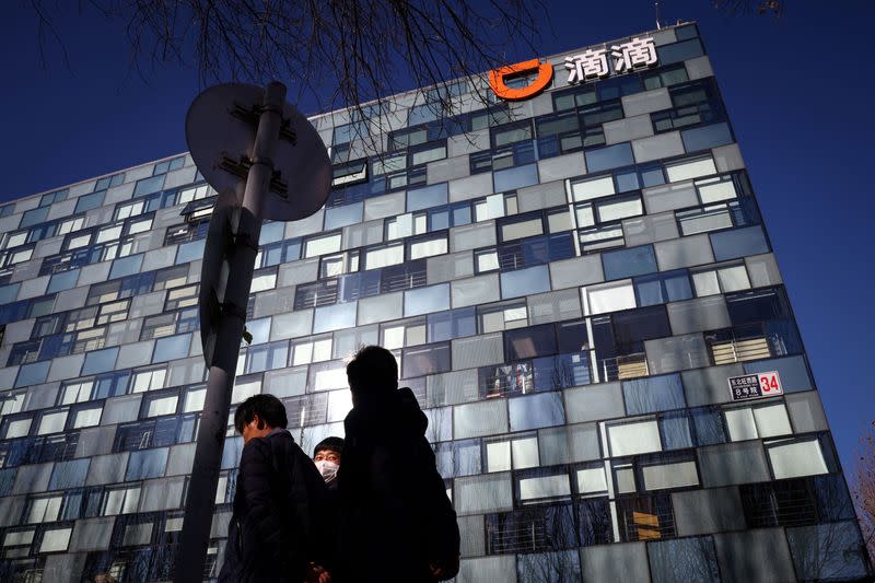 FILE PHOTO: People walk past the headquarters of the Chinese ride-hailing service Didi in Beijing