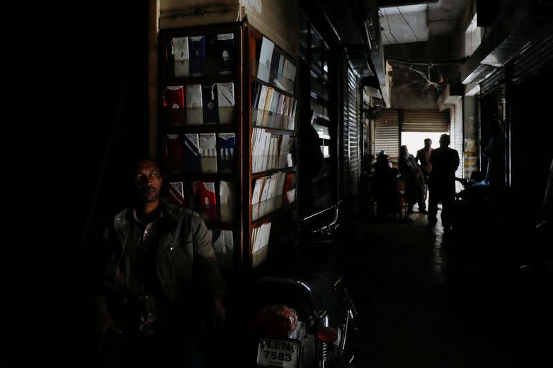 A man sits outside his shop during a country-wide power breakdown in Karachi