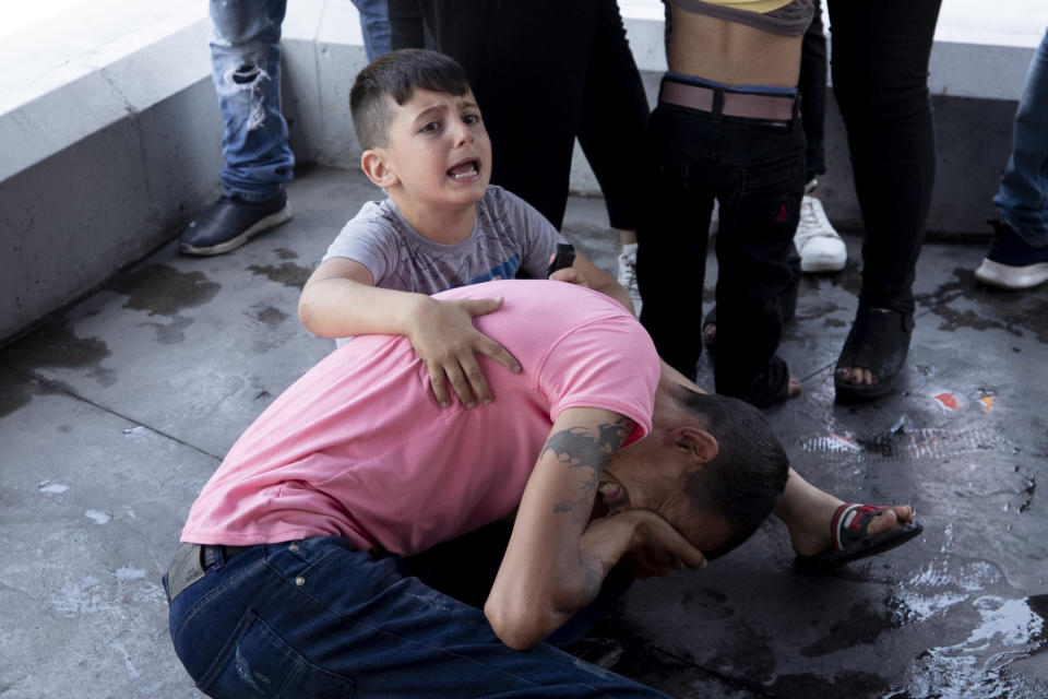 FILE - In this May 20, 2021, file photo, a boy screams for help after his father was injured when he was hit in the eye by a stone thrown by members of the Christian rightwing Lebanese Forces group, who attacked buses carrying Syrian voters, in the town of Zouk Mosbeh, north of Beirut, Lebanon. Mobs of angry Lebanese men attacked buses and cars carrying Syrians expatriates and others heading to the Syrian embassy in Beirut protesting against what they said was an organized vote for President Bashar Assad. (AP Photo/Hassan Ammar)