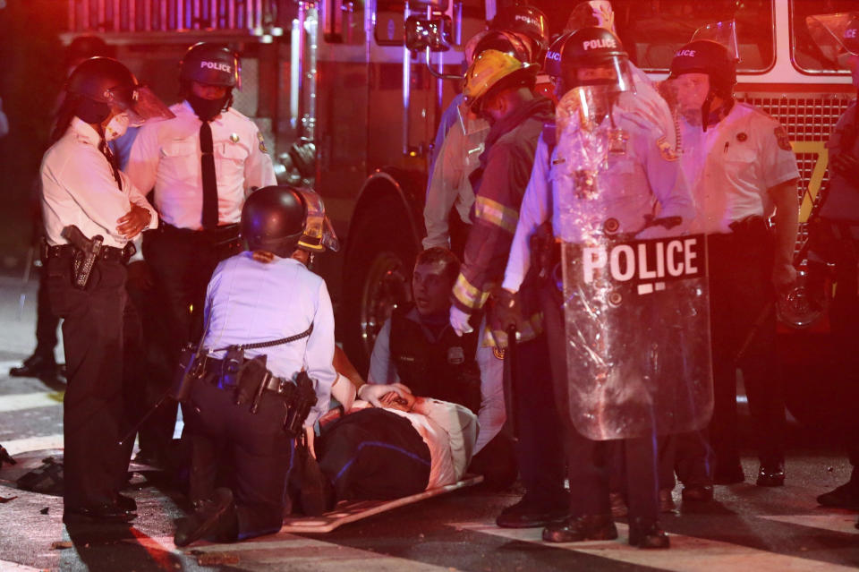 A police officer lies on the ground before being loaded into an ambulance on 52nd Street in West Philadelphia in the early hours of Tuesday, Oct. 27, 2020. Protesters gathered after police shot and killed a Black man in West Philadelphia on Monday. (Tim Tai/The Philadelphia Inquirer via AP)