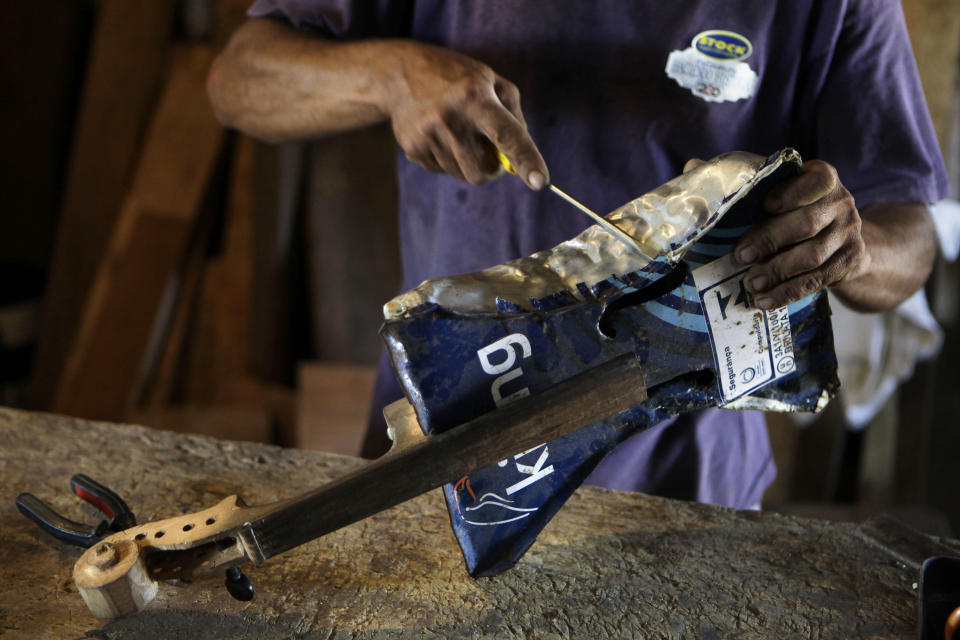 In this Dec. 11, 2012 photo, Nicolas Gomez makes a violin with recycled materials at his home in the Cateura, a vast landfill outside Paraguay's capital of Asuncion, Paraguay. Gomez, a trash picker and former carpenter, was asked by Favio Chavez, the creator of ìThe Orchestra of Instruments Recycled From Cateura," to make instruments out of materials from the dump to help keep the younger kids occupied. ìI only studied until the fifth grade because I had to go work breaking rocks in the quarries,î said Gomez, 48. (AP Photo/Jorge Saenz)