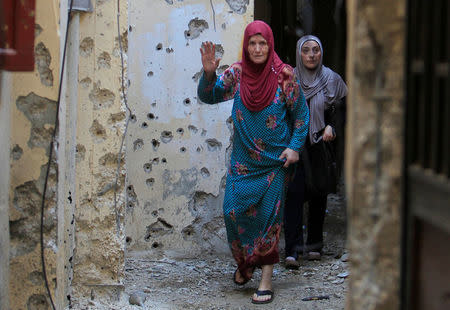 A woman gestures as she walks near bullet-riddled wall inside the Ain el-Hilweh refugee camp near Sidon, southern Lebanon, August 18, 2017. REUTERS/Ali Hashisho