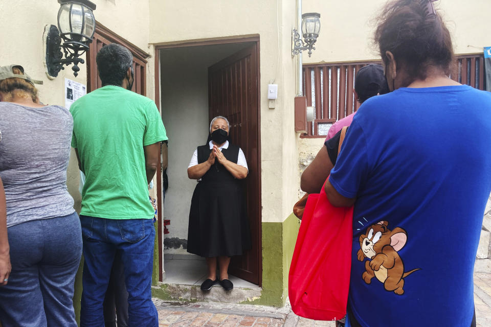 Isabel Turcios, director of the Casa del Migrante migrant services center delivers breakfasts of rice, beans and tortillas to migrants lined up outside, June 1, 2022 in Piedras Negras, Mexico. (AP Photo/Elliot Spagat)