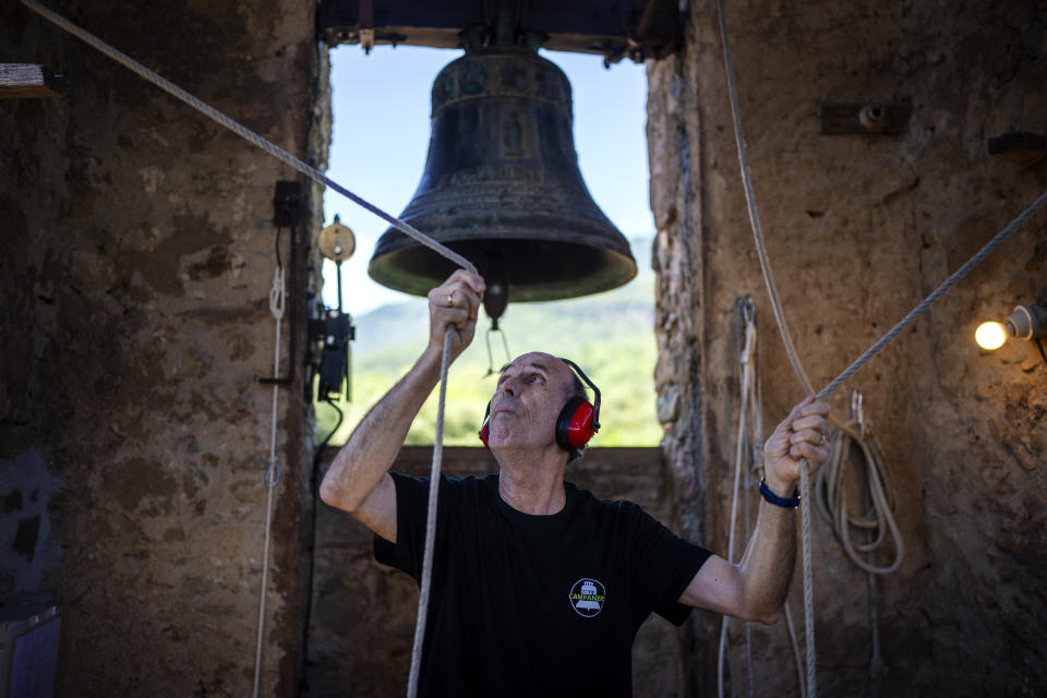 Josep-Maria Grosset, a student of the Vall d'en Bas School of Bell Ringers, performs playing two bronze bells at the church bell tower of the12th-century Sant Romà church, at the tiny village of Joanetes, about two hours north of Barcelona, Spain, Saturday, July 29, 2024. A school set up to revive the manual ringing of church bells has graduated its first class of 18 students after learning their ringing skills. (AP Photo/Emilio Morenatti)