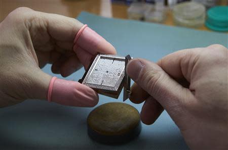 A watchmaker adjusts the components of the Autore 2TA watch model at Buccellati workshop in Chiasso March 14, 2014. REUTERS/Denis Balibouse