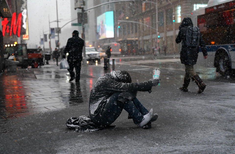 <p>A man begs for money in the snow along 42nd Street in Times Square in New York on March 21, 2018, as the fourth nor’easter in a month hits the tri-state area on the first full day of spring. (Photo: Timothy A. Clary/AFP/Getty Images) </p>