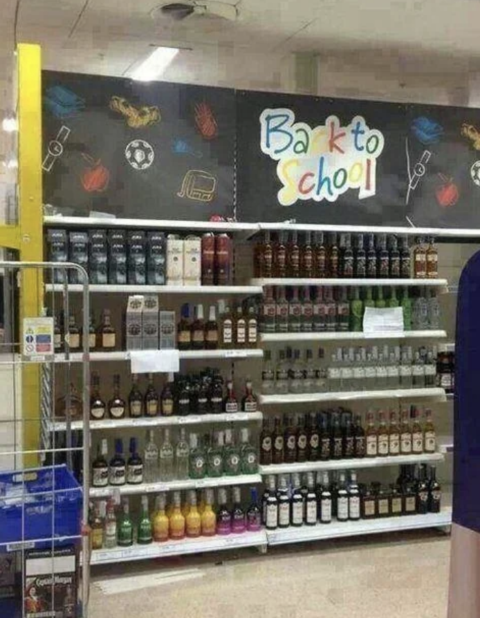 Semnul scrie „Înapoi la școală” deasupra unui raft cu băuturi într-un magazin, ceea ce implică umor în context