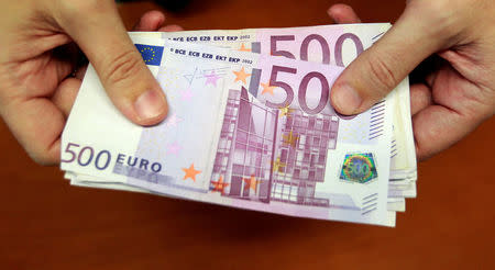 FILE PHOTO: A bank employee holds a pile of 500 euro notes at a bank branch in Madrid January 13, 2011. REUTERS/Andrea Comas/File Photo