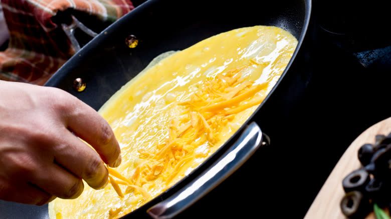 Person cooking omelet in pan