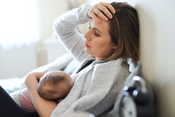 Mom breastfeeding her baby and looking tired