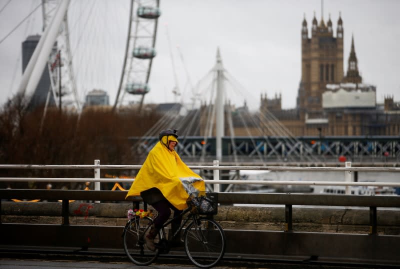 FILE PHOTO: Woman cycles across Waterloo Bridge during wet and windy weather in London