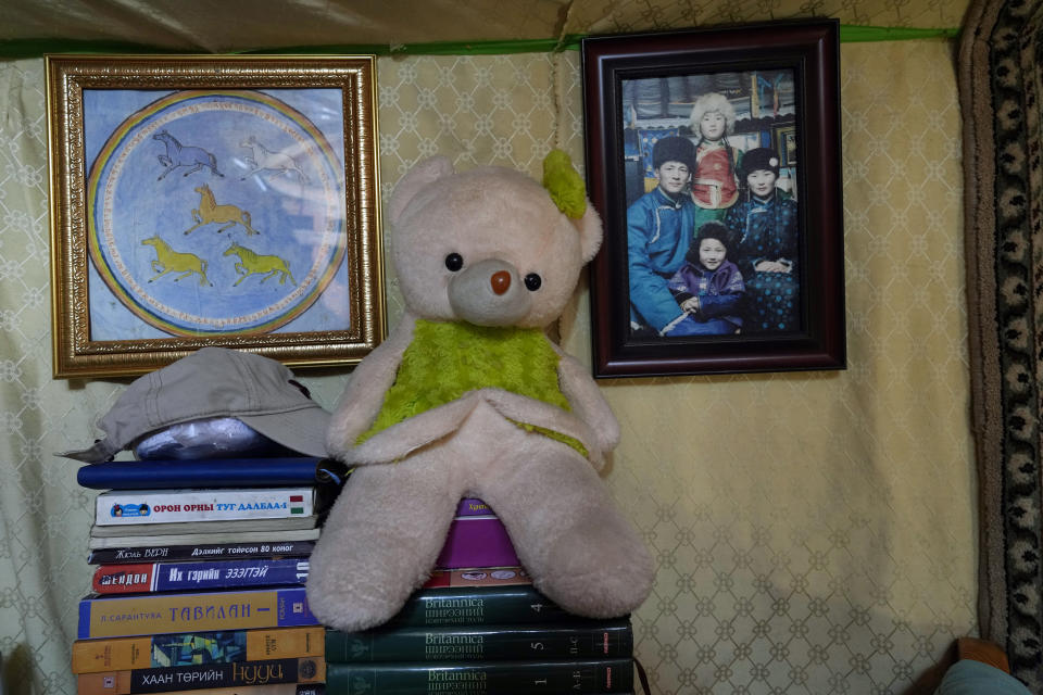 A family photograph of herder Agvaantogtokh, his wife, Nurmaa, and their children hangs in their ger along with a teddy bear and some books in the Munkh-Khaan region of the Sukhbaatar district, in southeast Mongolia, Saturday, May 13, 2023. “I won’t regret anything if my child won’t be a herder,” Nurmaa says. “I would like them to do what they aspire to do.” (AP Photo/Manish Swarup)