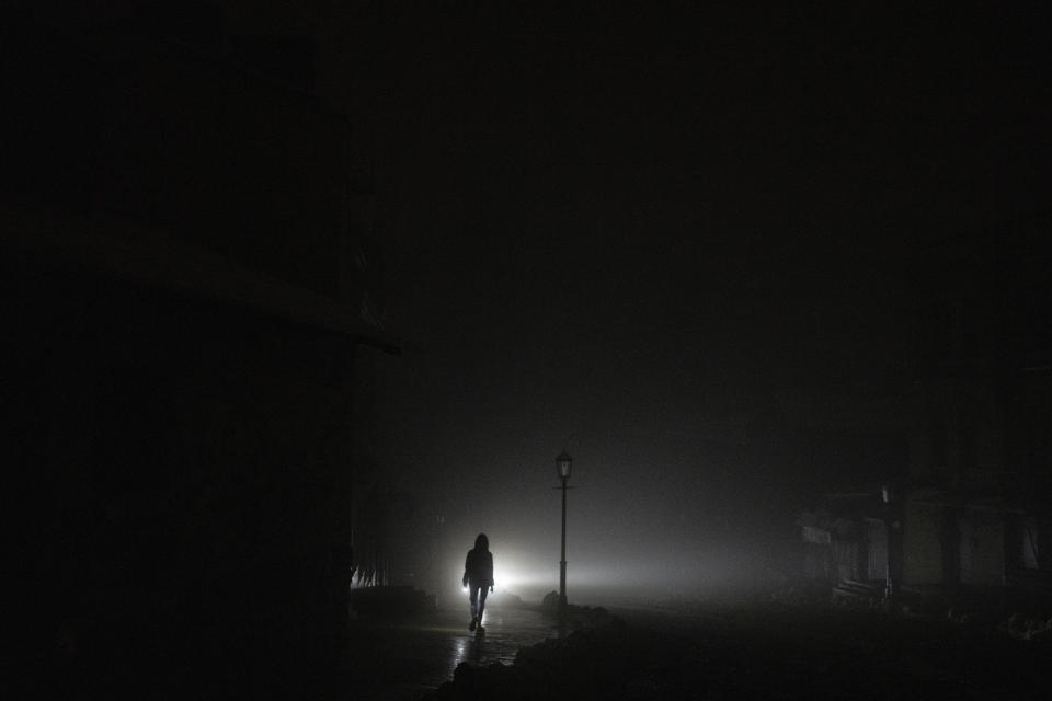 FILE - A woman walks through the city center which lost electrical power after yesterday's Russian rocket attack in Kyiv, Ukraine, Nov. 24, 2022. The hard realities of Ukraine’s capital are that a once comfortably livable city of 3 million people is now becoming a tough place to live. But Kyiv has hope, resilience and defiance in abundance. And perhaps more so now than at any time since Russia invaded Ukraine nine months ago. (AP Photo/Evgeniy Maloletka, File)