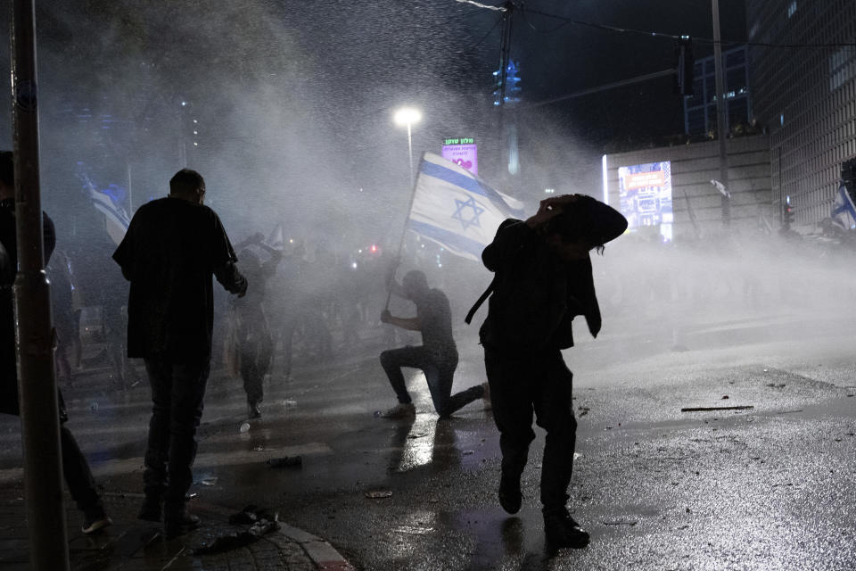 Israeli police use a water cannon to disperse demonstrators blocking a road during protests against plans by Prime Minister Benjamin Netanyahu's government to overhaul the judicial system, in Tel Aviv, Israel, Monday, March 27, 2023. Netanyahu has delayed his contentious judicial overhaul plan after a wave of mass protests. The Israeli leader said said he wanted "to avoid civil war" by making time to seek a compromise with political opponents. (AP Photo/Oded Balilty)