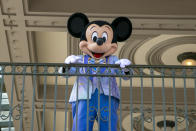 FILE - An actor dressed as Mickey Mouse greets visitors at the entrance to Magic Kingdom Park at Walt Disney World Resort, April 18, 2022, in Lake Buena Vista, Fla. Winnie the Pooh and Mickey Mouse have recently entered the public domain, making it possible for artists to use them freely. (AP Photo/Ted Shaffrey, File)