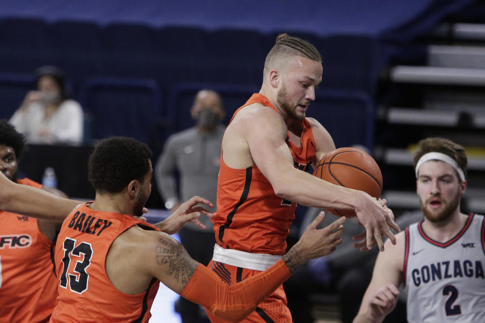 Pacific guard Broc Finstuen, center, goes after a rebound next to teammate Jeremiah Bailey, left, during the first half of the team's NCAA college basketball game against Gonzaga in Spokane, Wash., Saturday, Jan. 23, 2021. (AP Photo/Young Kwak)