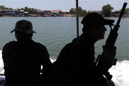 Armed police provide security to Police Major General Thatchai Pitaneelaboot as they sail up a river in towards a trafficking camp in Satun, southern Thailand March 27, 2014. REUTERS/Andrew RC Marshall