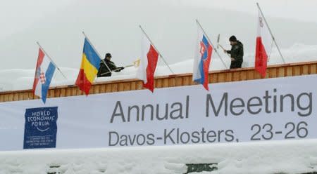 FILE PHOTO: Workers shovel snow from the roof of the congress centre, the venue of the upcoming World Economic Forum (WEF) in the Swiss mountain resort of Davos, Switzerland, January 18, 2018  REUTERS/Arnd Wiegmann ,