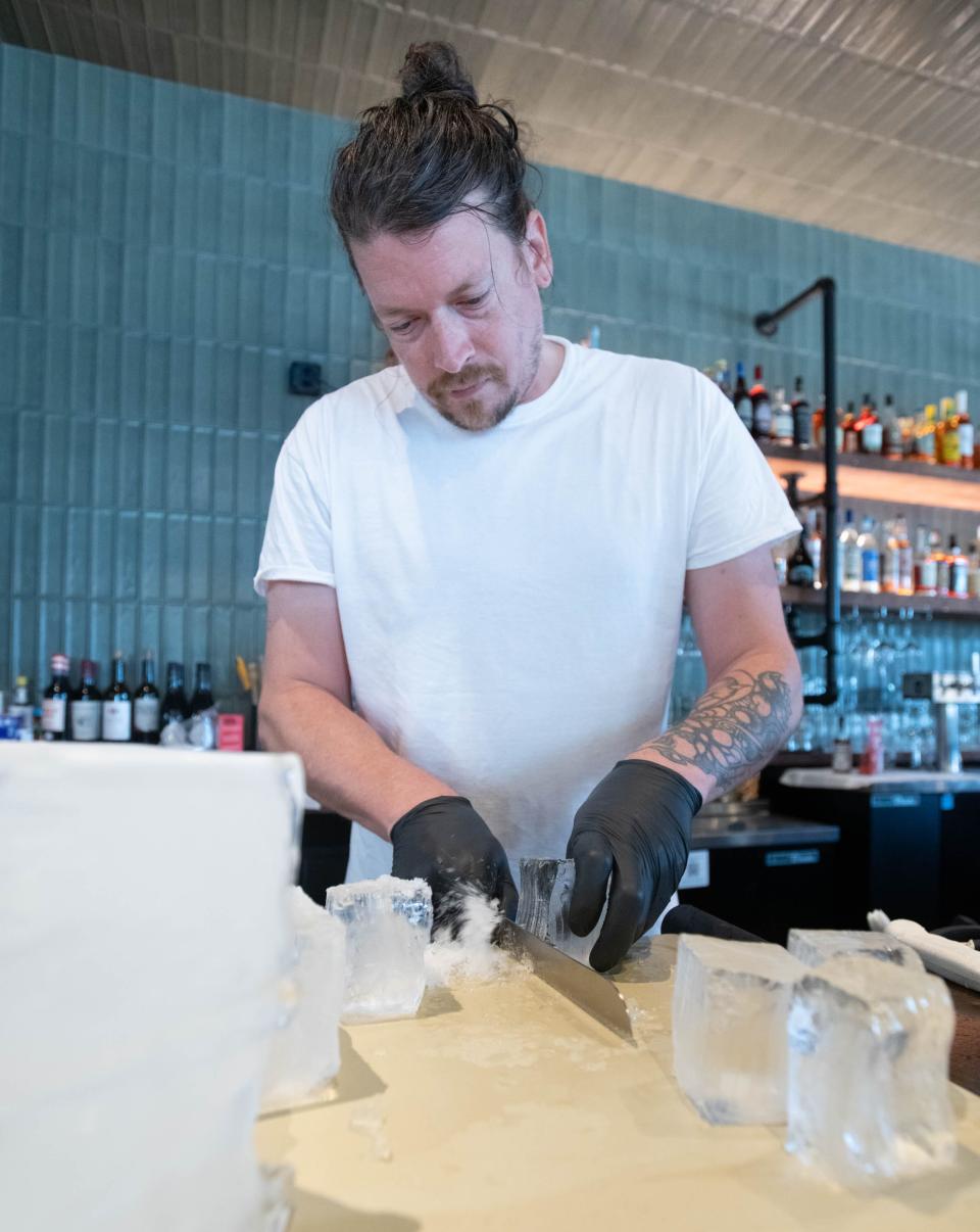 Bar and front of house manager Nate Simmons hand cuts ice at the new location of the Union Public House at 36 East Garden Street in Pensacola on Friday, Aug, 25, 2023.