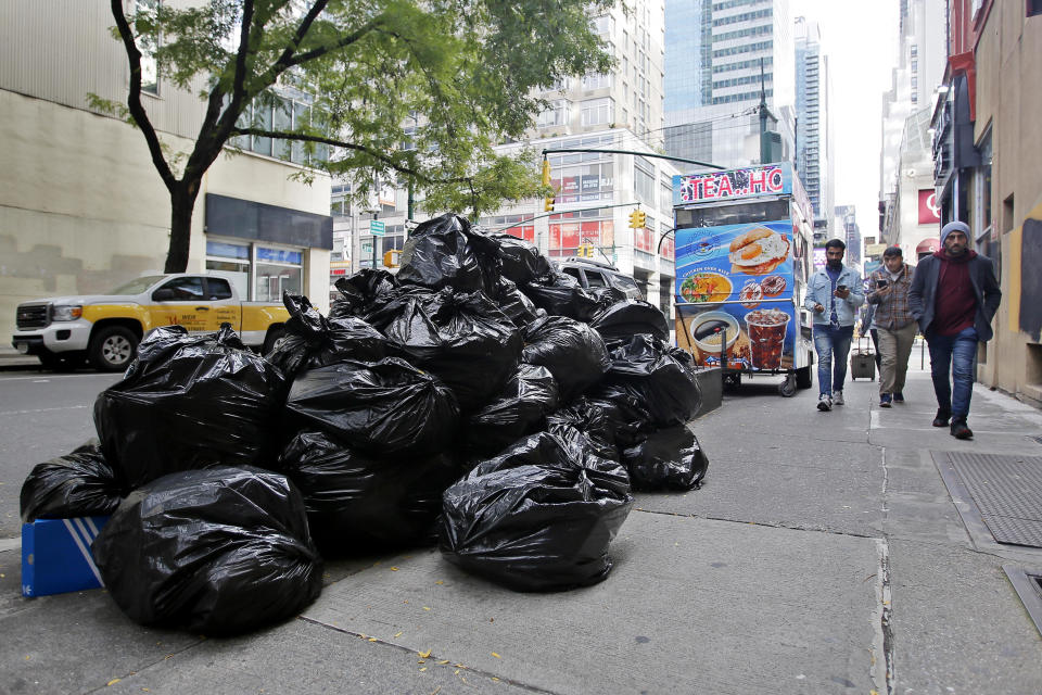 People make their way past a pile of trash bags on a New York City sidewalk. / Credit: Leonardo Munoz / VIEWpress via Getty Images
