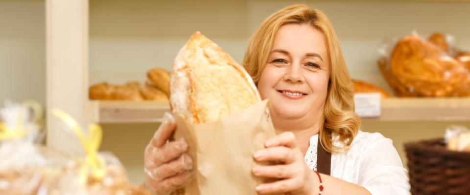 Woman handing bread over counter in bakery