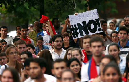 A woman holds a sign reading NO during a students' rally against a proposed amendment that would allow Paraguay's president to stand for re-election in Asuncion, Paraguay, April 2, 2017. REUTERS/Marcos Brindicci