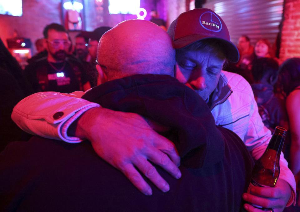 James Pence, co-owner, back, hugs Anthony Gonzalez, front, on Tuesday, Dec. 19, 2023, at Bar:PM in the Carondelet neighborhood in St. Louis. Friends and supporters gathered at the bar after a police officer drove into the bar early Monday morning. Co-owner Chad Morris was arrested following the incident. Gonzalez said he is a regular at the bar. "We can't afford to lose this place," Gonzalez said. (Christine Tannous/St. Louis Post-Dispatch via AP)