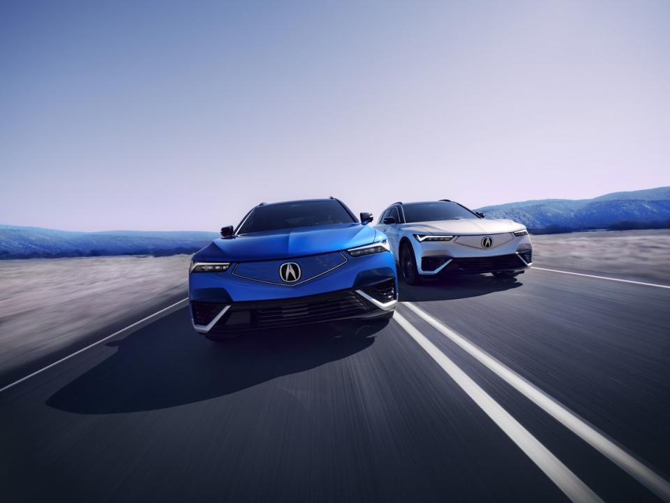 a couple of cars driving on a road with mountains in the background