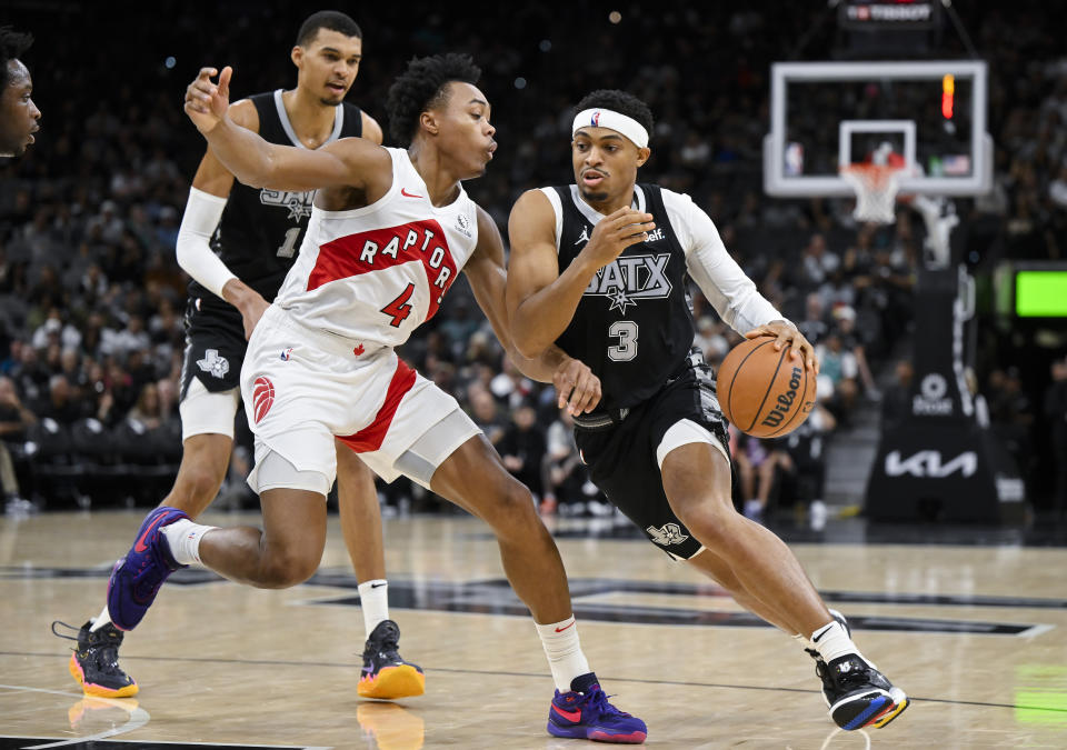 San Antonio Spurs' Keldon Johnson (3) drives against Toronto Raptors' Scottie Barnes (4) during the first half of an NBA basketball game, Sunday, Nov. 5, 2023, in San Antonio. (AP Photo/Darren Abate)