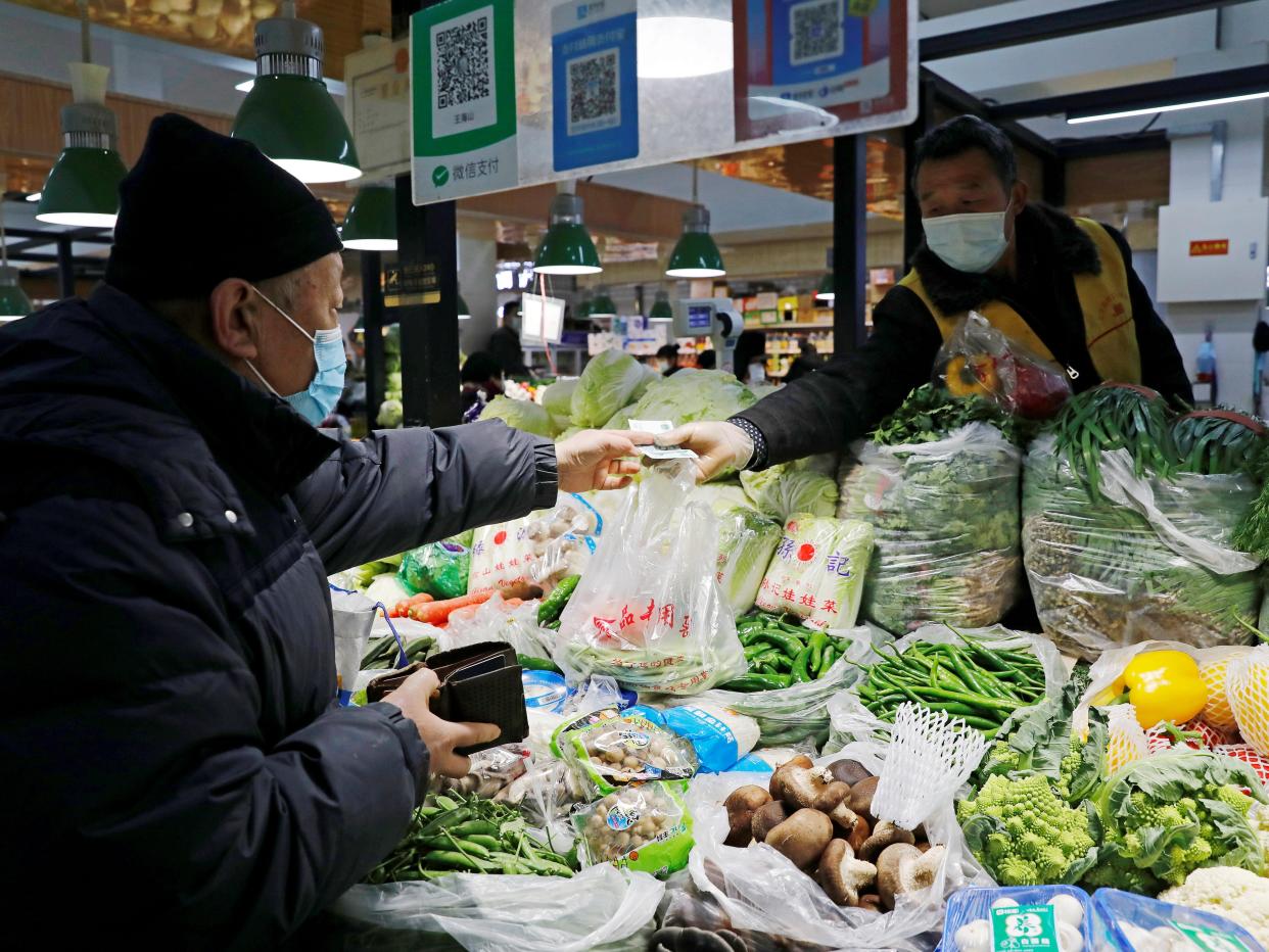 People wearing face masks shop at a market, following new cases of the coronavirus disease (COVID-19) in the country, in Beijing, China January 11, 2021.