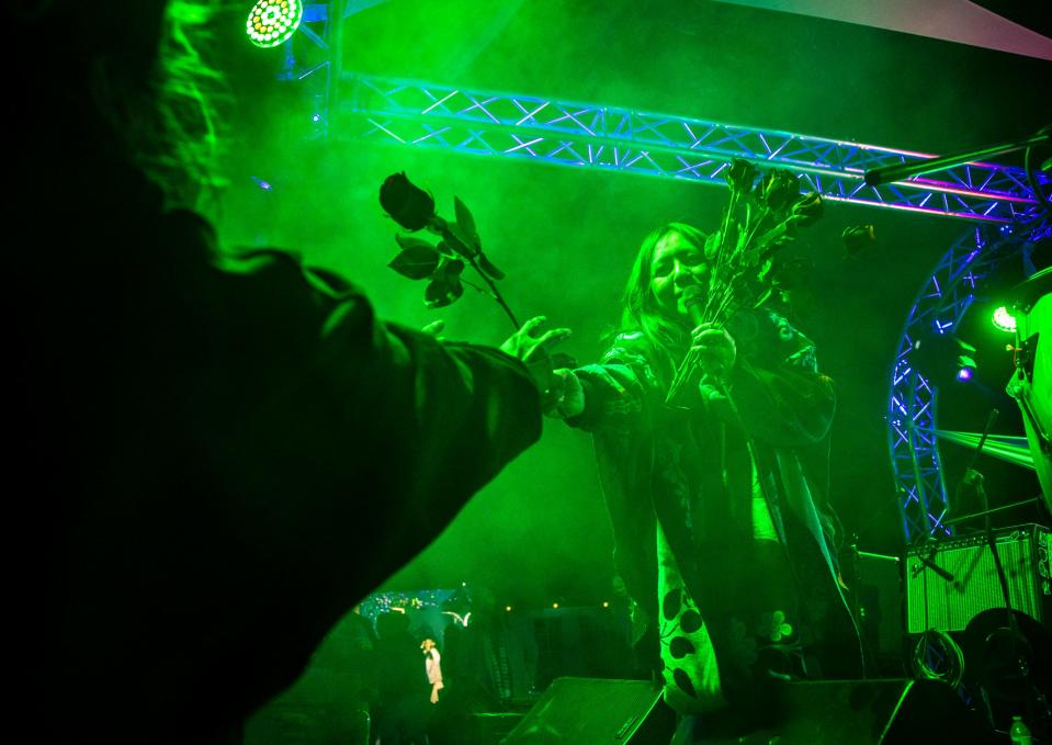 Giselle Woo, lead singer of Giselle Woo & The Night Owls, hands a rose to a festivalgoer during her band's headlining set at Desert Underground in Coachella, Calif., Saturday, Jan. 28, 2023. 