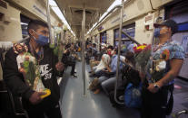 Devotees travel on the subway with their Saint Jude statues during the annual pilgrimage honoring Jude, the patron saint of lost causes, in Mexico City, Wednesday, Oct. 28, 2020. Thousands of Mexicans did not miss this year to mark St. Jude's feast day, but the pandemic caused Masses to be canceled and the rivers of people of other years outside the San Hipolito Catholic church were replaced by orderly lines of masked worshipers waiting their turn for a blessing. (AP Photo/Marco Ugarte)