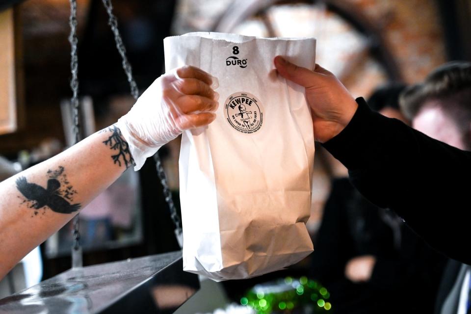 A customer grabs a bag of food at Weston's Kewpee Sandwich Shop on Thursday, March 16, 2023, in Lansing. The downtown Lansing staple is celebrating its 100th anniversary. 