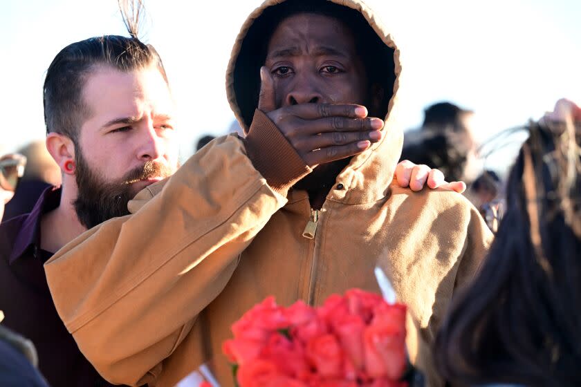 Joshua Thurman, center, is comforted by Ryane Flipp at a makeshift memorial near Club Q in Colorado Springs, Colo.