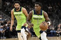 Minnesota Timberwolves' Anthony Edwards (1) runs past teammate Karl-Anthony Towns during the first half of an NBA basketball game against the San Antonio Spurs on Monday, March 14, 2022, in San Antonio. (AP Photo/Darren Abate)