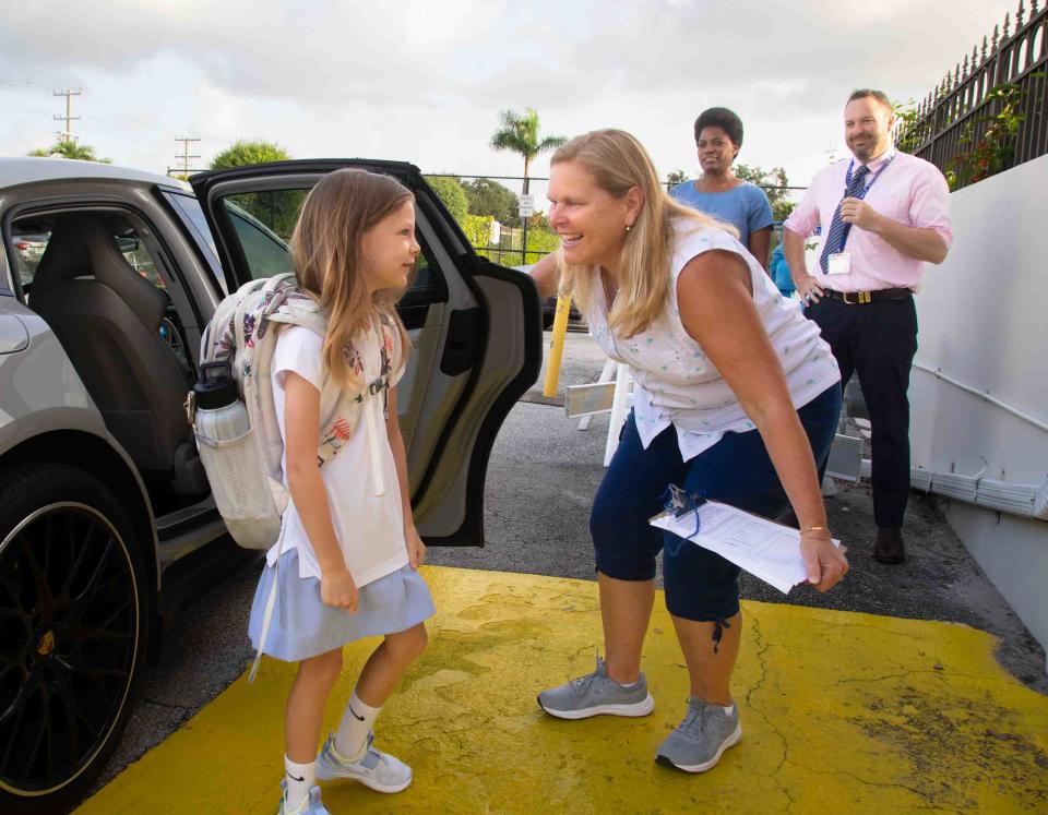 Early Childhood Montessori teacher Leslie Leckrone greets second grader Abby Wren in the car loop at Rosarian Academy on Tuesday.